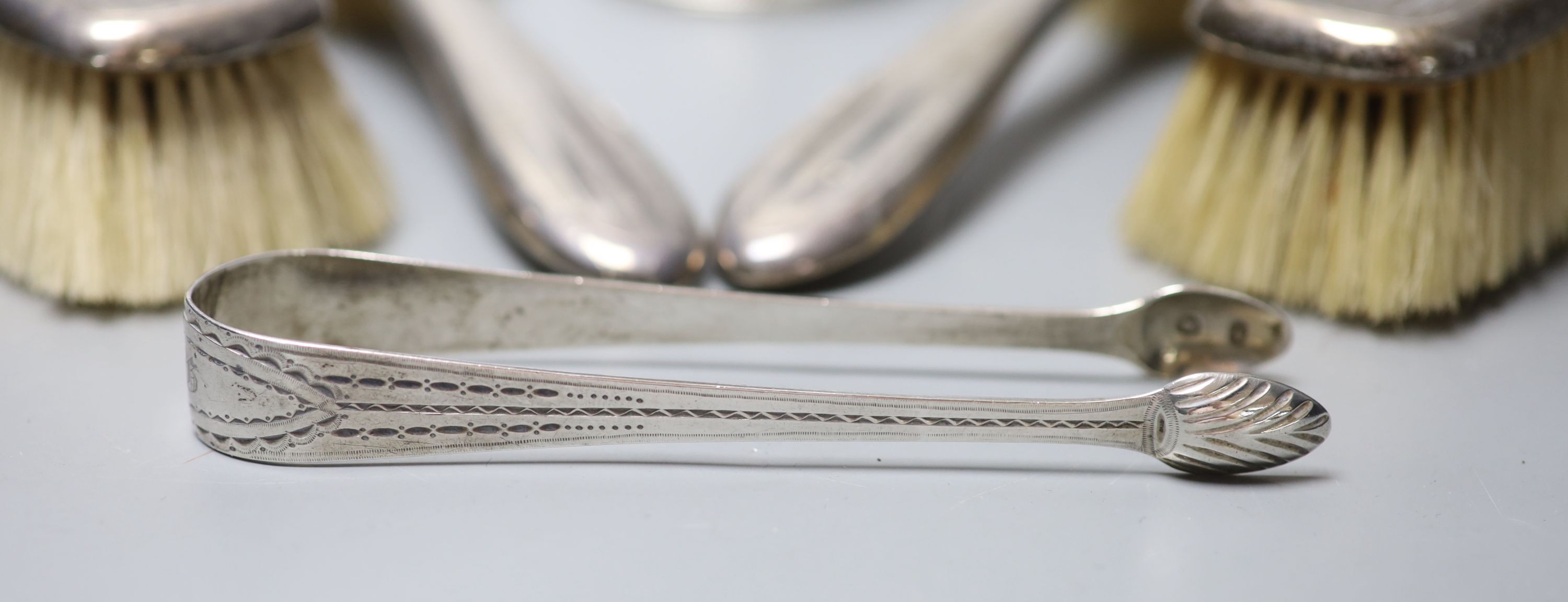 A Victorian engraved silver goblet, London, 1875, 6.3cm, a pair of silver sugar tongs and four silver mounted brushes.